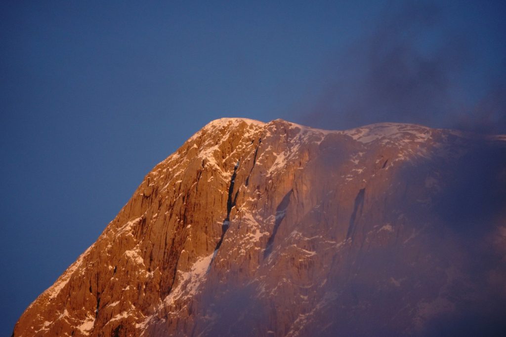 Bergmassiv im warmen Licht zwischen Wolken und blauem Himmel